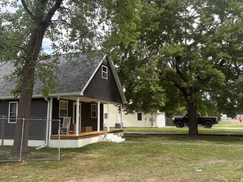Same dark-sided home with the fallen tree removed, roof intact, and the front yard cleaned in Tampa, FL